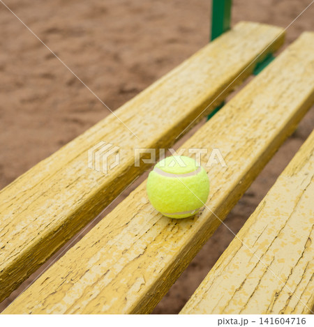 Tennis ball on weathered yellow wooden bench outdoors Tennis ball on weathered yellow wooden bench outdoors 141604716