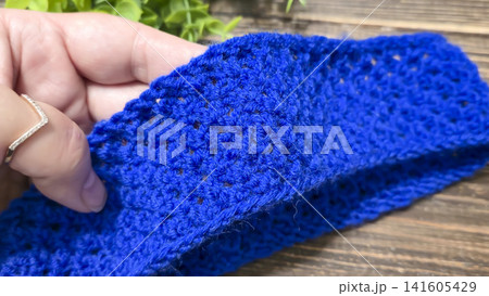 A blue thread pattern on a wooden background. Knitting tutorial and sample of the finished piece. 141605429