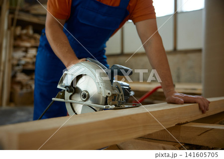 Professional artisan utilizes circular saw to carve wood securely with safety measures 141605705