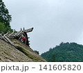山あいに佇む茅葺き屋根から覗く赤天狗 141605820