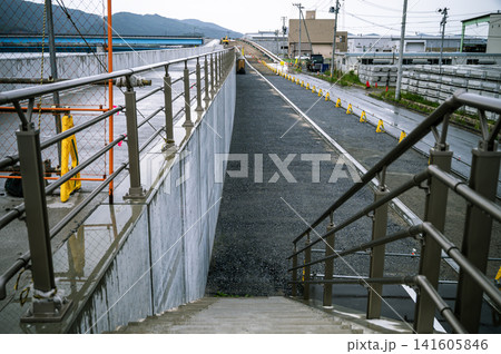 雨が降る中で整備が進む高台の階段と新設されたコンクリート防潮堤工事現場の風景 141605846