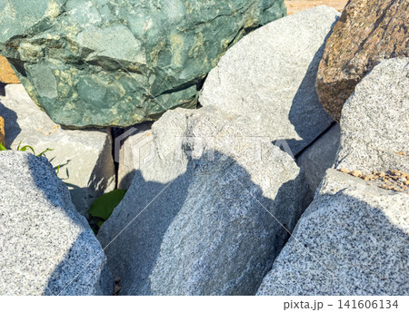 Various textured rocks and stones in natural outdoor setting with sunlight casting shadows Various textured rocks and stones in natural outdoor setting with sunlight casting shadows 141606134