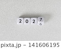 Year 2026 changing to 2027 on dice, glitter festive gray background. New year change concept 141606195