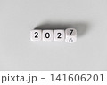 Year 2026 changing to 2027 on dice, gray background. New year change concept 141606201