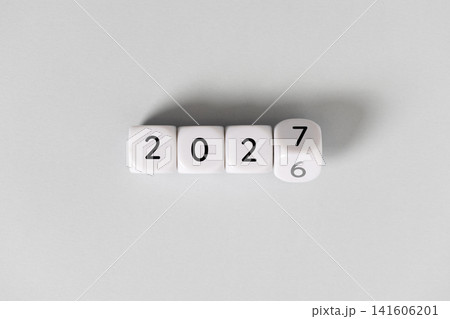 Year 2026 changing to 2027 on dice, gray background. New year change concept 141606201