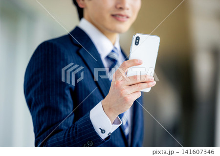 オフィスでスマホを操作する若い男性 141607346