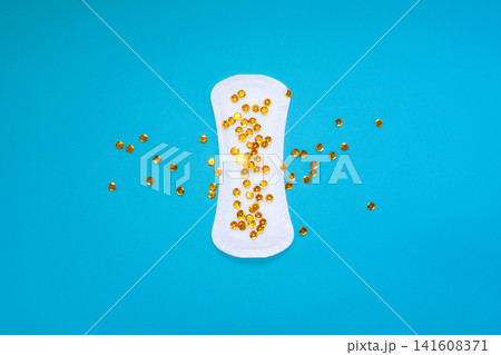 Sanitary Pad with Gold Sequins Representing Urinary Leakage on Blue Background Sanitary Pad with Gold Sequins Representing Urinary Leakage on Blue Background 141608371