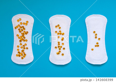 Three Sanitary Pads with Gold Sequins Representing Different Levels of Urinary Leakage on blue Background Three Sanitary Pads with Gold Sequins Representing Different Levels of Urinary Leakage on blue Background 141608399