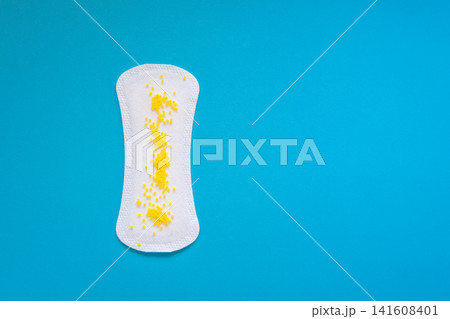 Sanitary Pad with Yellow Beads Symbolizing Urinary Leakage on Blue Background Sanitary Pad with Yellow Beads Symbolizing Urinary Leakage on Blue Background 141608401