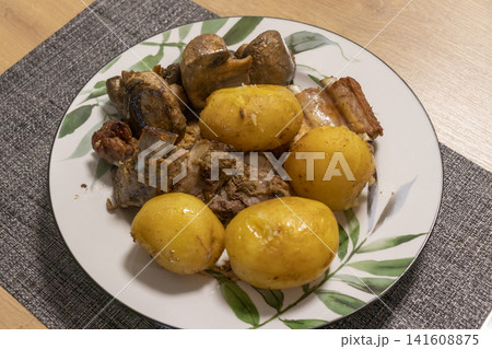 Roasted pork ribs served with whole boiled potatoes and fried mushrooms 141608875