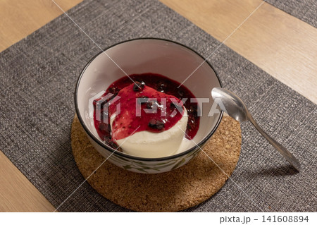 Italian panna cotta dessert topped with red berry coulis in a ceramic bowl 141608894