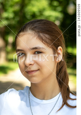 Portrait of a teenage girl smiling outdoors in a green park on a sunny day Portrait of a teenage girl smiling outdoors in a green park on a sunny day 141609509