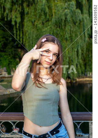 Teen girl portrait on a bridge in a park with willow trees and casual summer style 141609562