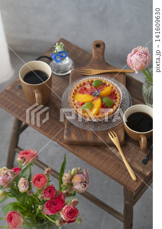 木製テーブルに並ぶフルーツタルトと2杯のホットコーヒー 花のあるカフェタイム 木製テーブルに並ぶフルーツタルトと2杯のホットコーヒー 花のあるカフェタイム 141609630