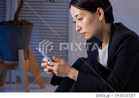 スマホを見て落ち込む女性 141610187