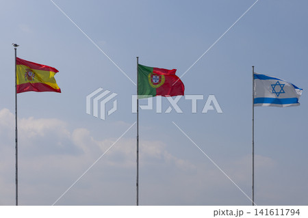 Flags of Spain, Portugal and Israel aligned above a soft bank of clouds Flags of Spain, Portugal and Israel aligned above a soft bank of clouds 141611794