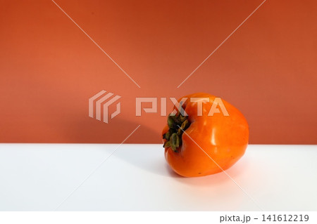 Persimmon fruit on two-colored background. Persimmon fruit on two-colored background. 141612219