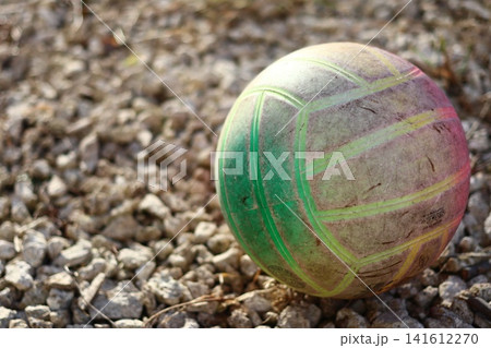 A volleyball ball is lying on a gravel surface. A volleyball ball is lying on a gravel surface. 141612270