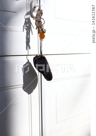 Keys with a case are hanging on the gate. Keys with a case are hanging on the gate. 141612367