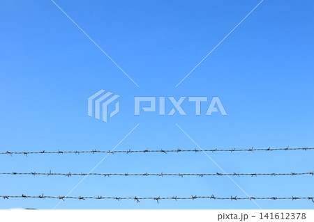 Barbed wire fence over blue sky. Barbed wire fence over blue sky. 141612378