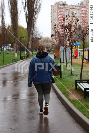 A woman walks in the park during the rain. A woman walks in the park during the rain. 141612442