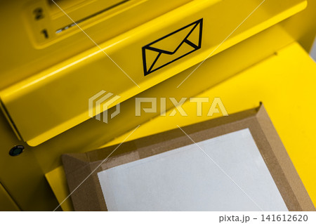 Brown parcel with a white label rests near a yellow mailbox at a self service kiosk, illustrating efficient postal automation. Brown parcel with a white label rests near a yellow mailbox at a self service kiosk, illustrating efficient postal automation. 141612620