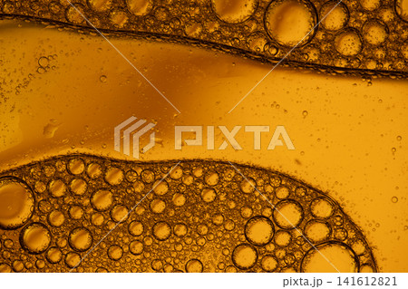Golden liquid with oil and water separation creating tiny bubbles and abstract patterns Golden liquid with oil and water separation creating tiny bubbles and abstract patterns 141612821