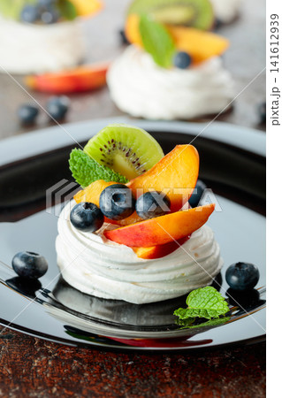 Pavlova dessert with nectarines, kiwis, blueberries, and mint. Pavlova dessert with nectarines, kiwis, blueberries, and mint. 141612939