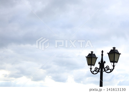 A vintage-style street lamp under a cloudy sky. 141613130