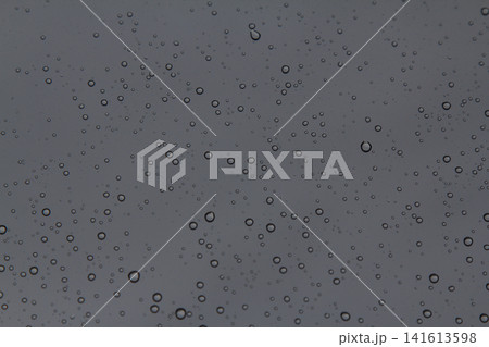 Rain drops on the glass in the spring afternoon. Close up of a window with rain drops falling down.The rain drops on household windows. Focus on rain drops. concept of sadness, frustration Rain drops on the glass in the spring afternoon. Close up of a window with rain drops falling down.The rain drops on household windows. Focus on rain drops. concept of sadness, frustration 141613598