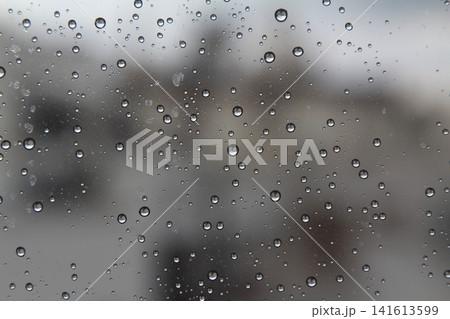Rain drops on the glass in the spring afternoon. Close up of a window with rain drops falling down.The rain drops on household windows. Focus on rain drops. concept of sadness, frustration 141613599