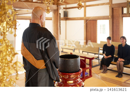 本堂で法要を行うお坊さんの後ろ姿と喪服の参列者 本堂で法要を行うお坊さんの後ろ姿と喪服の参列者 141613621