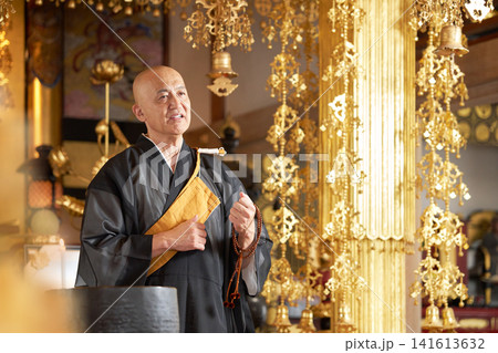 寺院の本堂で数珠を手に法話をする僧侶 寺院の本堂で数珠を手に法話をする僧侶 141613632