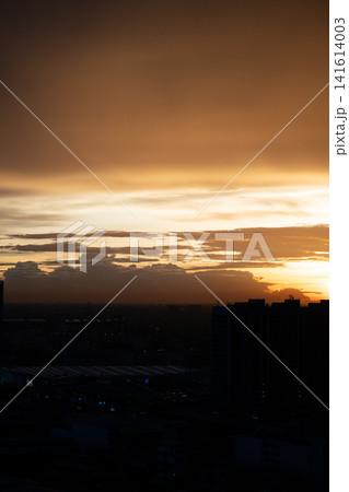 Sunset sky cloud city silhouette horizon dusk orange city skyline under dramatic cloud at dusk with warm light and dark building silhouette 141614003