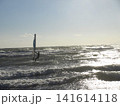 逆光の海でウィンドサーフィンを楽しむ人物と波が輝く海の風景 141614118