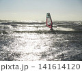 夕方の海でウィンドサーフィンをするシルエットと波の風景 141614120