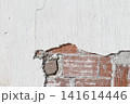 background of a damaged white plastered wall revealing red brick masonry structure 141614446