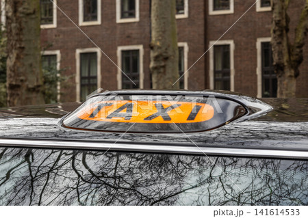 Taxi roof light on black vehicle parked in city Taxi roof light on black vehicle parked in city 141614533