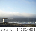 朝霧に包まれた海岸と波打ち際を歩く人々、海辺の小屋がある湘南の風景 141614634