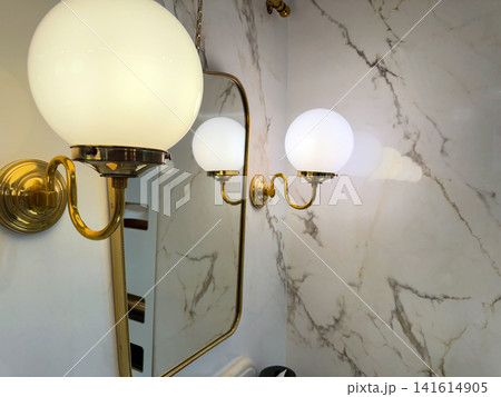 Classic brass wall light beside bathroom mirror interior Classic brass wall light beside bathroom mirror interior 141614905
