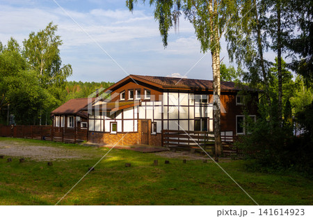 A wooden rural house in the forest. Nice cottage with beautiful garden in a countryside. A wooden rural house in the forest. Nice cottage with beautiful garden in a countryside. 141614923