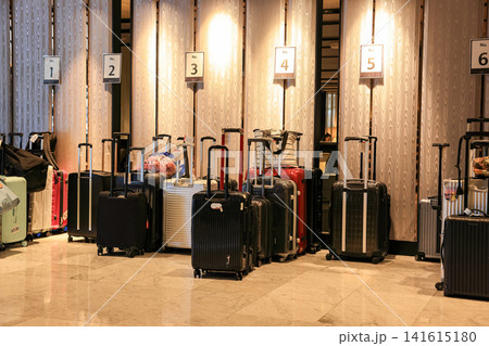 A large group of traveler's luggage organizing in a modern hotel lobby, A lot of tourist multicolored suitcases in the loading zone. A large group of traveler's luggage organizing in a modern hotel lobby, A lot of tourist multicolored suitcases in the loading zone. 141615180