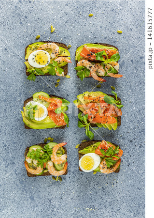 Healthy snack or appetizer toast with salmon, avocado, shrimps, eggs, cucumber, lambs lettuce or corn salad and parsley Healthy snack or appetizer toast with salmon, avocado, shrimps, eggs, cucumber, lambs lettuce or corn salad and parsley 141615777