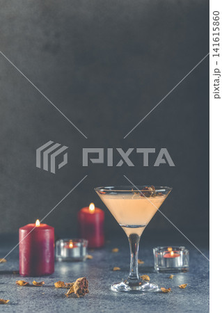 Summer grapefruit martini cocktail with dried roses flowers and petals, surrounded candles on dark gray table surface Summer grapefruit martini cocktail with dried roses flowers and petals, surrounded candles on dark gray table surface 141615860