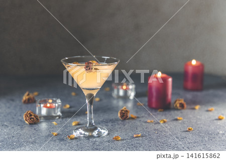 Summer grapefruit martini cocktail with dried roses flowers and petals, surrounded candles on dark gray table surface Summer grapefruit martini cocktail with dried roses flowers and petals, surrounded candles on dark gray table surface 141615862