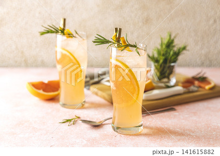 Two glasses of Paloma cocktails with tequila fresh grapefruit juice combined and rosemary. Light pink concrete surface. Two glasses of Paloma cocktails with tequila fresh grapefruit juice combined and rosemary. Light pink concrete surface. 141615882