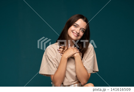 Young woman showing gratitude and appreciation, smiling with hands on chest against a dark background Young woman showing gratitude and appreciation, smiling with hands on chest against a dark background 141616509