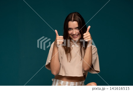 Young woman smiling and giving two thumbs up, showing approval, success, and positive support Young woman smiling and giving two thumbs up, showing approval, success, and positive support 141616515