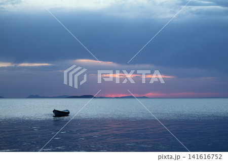 Sunset in the sea with a boat. A picture of a small boat with a beautiful sunset background. Sunset in the sea with a boat. A picture of a small boat with a beautiful sunset background. 141616752
