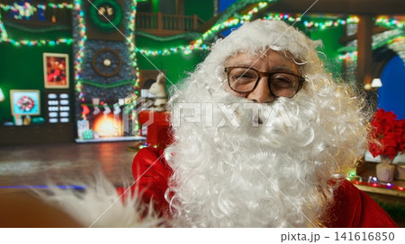 POV of Santa Claus talking to kids requesting gifts, filming video. Person impersonating Santa Claus talking with children about Christmas gifts, recording with selfie phone camera 141616850